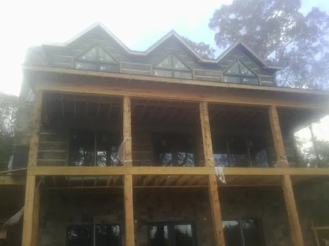 Dormers and porch framing on a large log home under construction — Roof Coating work by our crew in La Rue