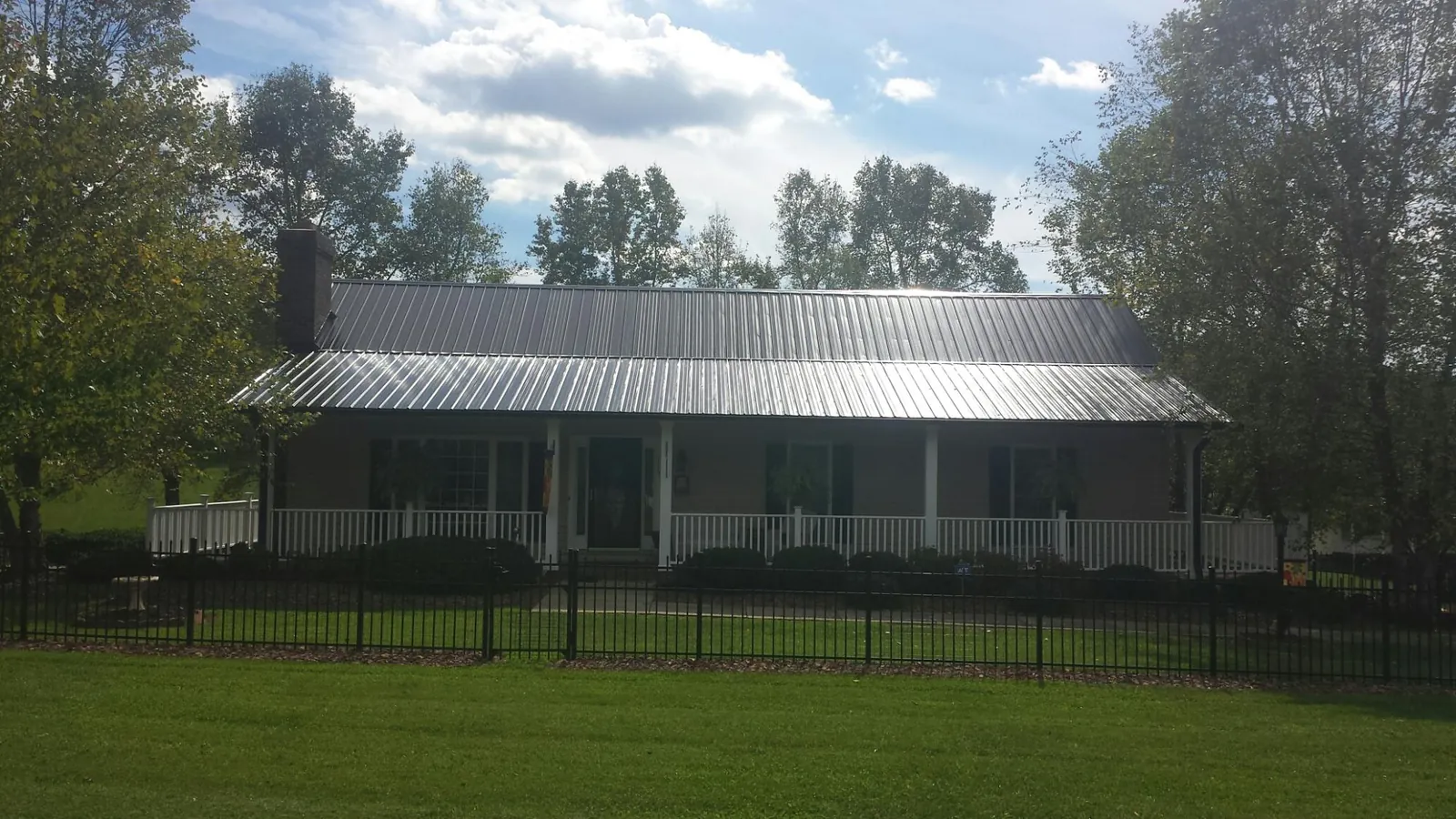 Gray metal roof on a brick ranch with a full width front porch — Gutter Guard Installation work by our crew in La Rue