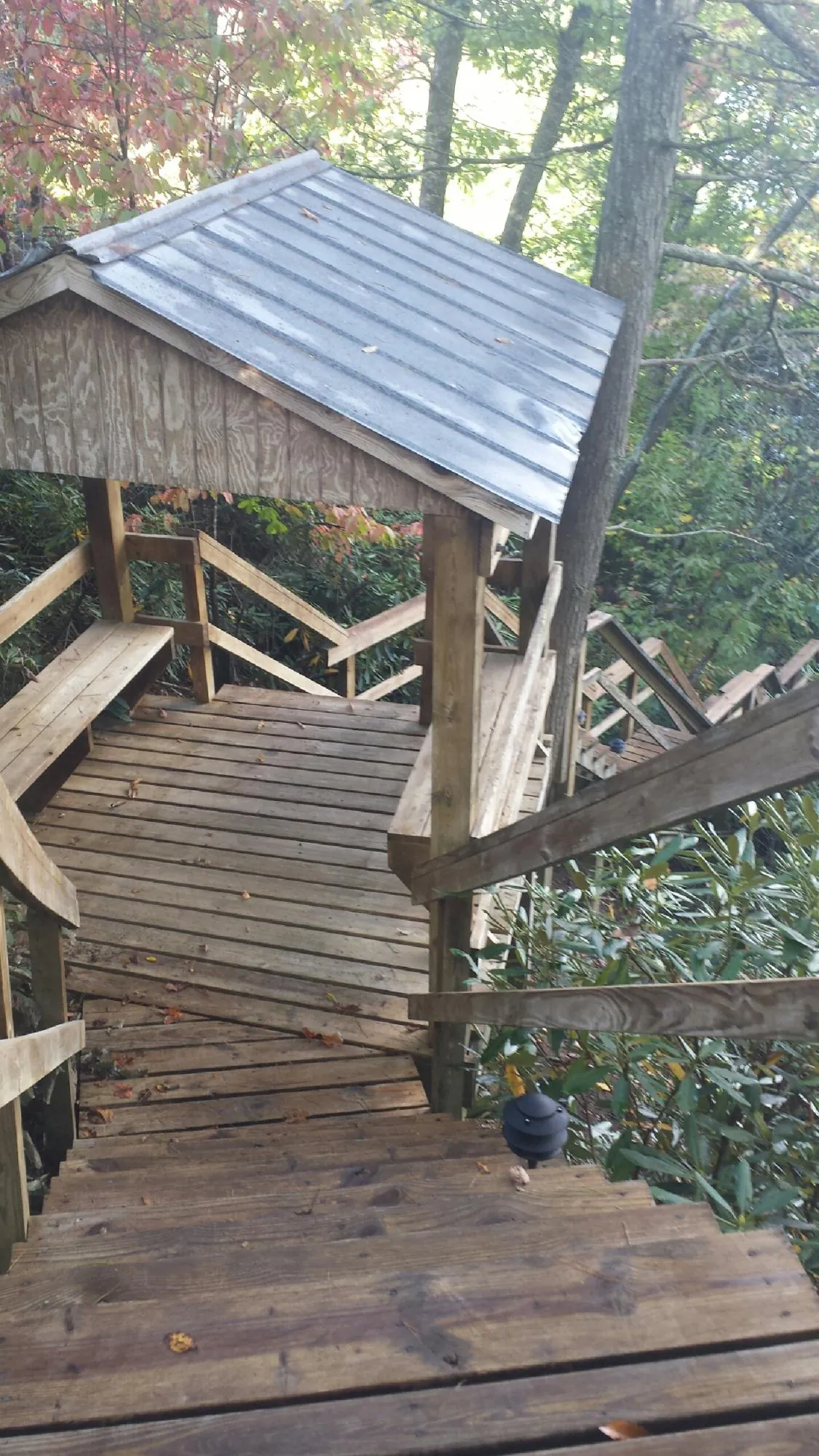 Metal roofed shelter over wooden steps on a wooded walkway — Skylight Repair & Installation work by our crew in La Rue